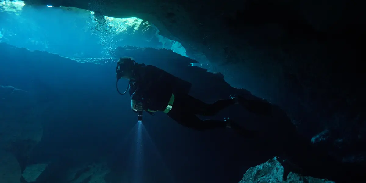 Buzo certificado bajo la luz natural de la caverna en el Cenote Chikin Ha